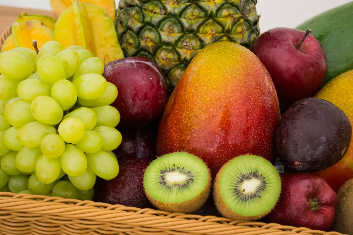 Korb mit Trauben, Kiwi, Äpfeln und weiteren Früchten